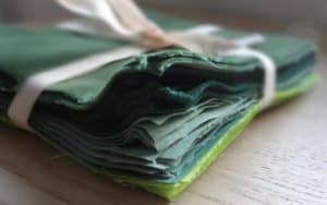 Des carrés de tissu vert, préparé pour un atelier créatif chez Repatchit