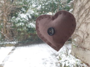 Cœur en lin foncé avec bouton sur fond de neige